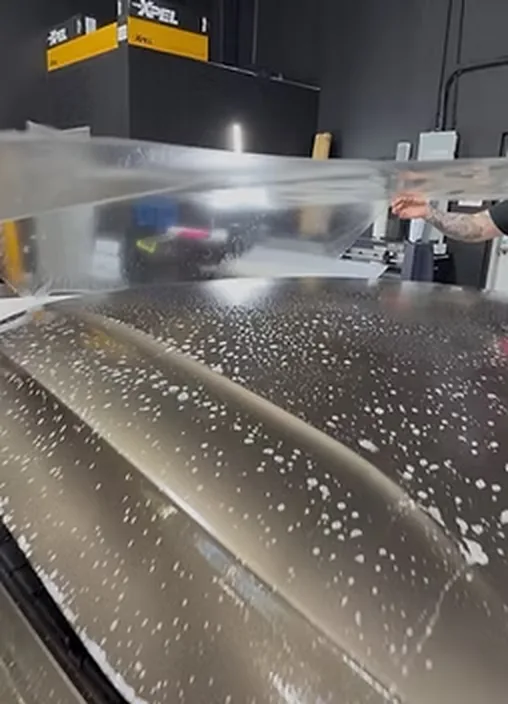 Film wet-applied across a car hood